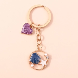 Dettaglio portachiavi sirena con cuore glitter viola e anello dorato con conchiglia