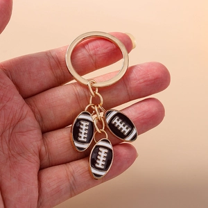 Portachiavi rugby con tre ciondoli in smalto bianco e nero su un anello in metallo dorato