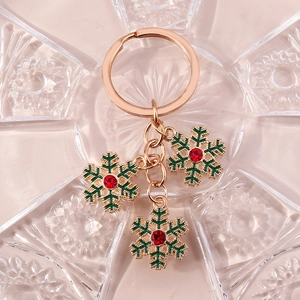 Détail d'un porte-clés flocon de neige de Noël avec émail vert et strass rouges