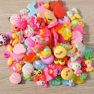 Flat lay of colorful resin animal and flower charms for DIY crafts on wood background