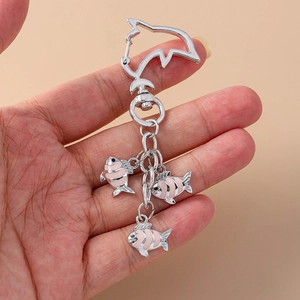 Cute dolphin shaped metal keychain with three pink striped fish pendants on hand