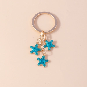 Détails de trois breloques étoile de mer en émail bleu sur un porte-clés en métal doré
