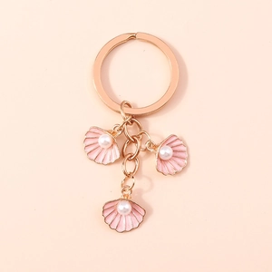 Portachiavi con conchiglia rosa in oro rosa e perle su sfondo albicocca delicato