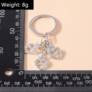 Détail de porte-clés cœur argenté avec strass et gravure Queen sur une règle