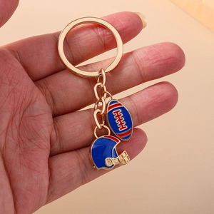 Porte-clés rugby américain et casque avec chaîne dorée tenu à la main sur fond kaki