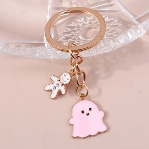 Détail du porte-clés doré avec charms de fantôme rose et bonhomme de pain d'épices