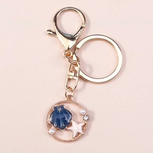 Dettaglio del portachiavi a stella marina e conchiglia dorata con perle e strass blu