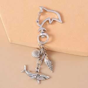 Detail of shark and seashell pendants on a dolphin-shaped keychain in antique finish