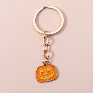Gros plan du porte-clés citrouille d'Halloween doré avec pendentif en émail orange