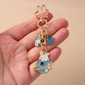 Détail du porte-clés lapin planète doré avec charms saturne bleu et lapin émail