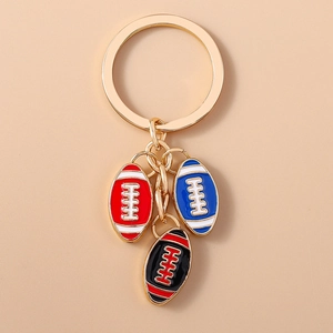 Dettaglio di portachiavi da rugby con ciondoli in smalto rosso blu e nero su anello oro