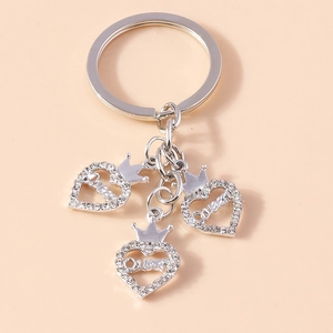 Détail de pendentifs en cœur argentés avec strass blancs et gravure Queen