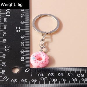 Pink cartoon donut keychain with chocolate text measured against a ruler for scale