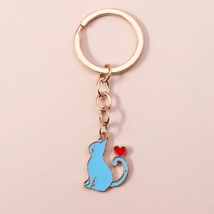Gros plan d'un porte-clés chat bleu avec cœur et anneau doré sur fond rose doux