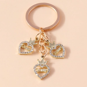 Détail du porte-clés coeur doré avec lettrage Queen et strass sur fond rose doux