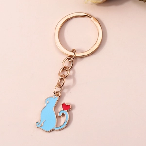 Détail d'un porte-clés chat en émail bleu avec un petit cœur rouge et un anneau doré