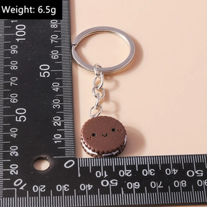 Close-up of a realistic sandwich cookie keychain with a smiling face and measurement ruler