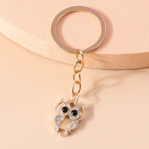 Fashionable golden owl keychain with sparkling rhinestones and black gem eyes on a round platform