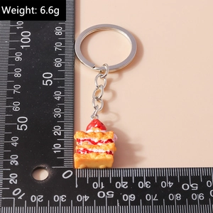 Macro detail of a 6.6g strawberry cake keychain with silver ring and measurement scale