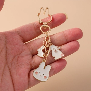 Porte-clés lapin doré mignon avec breloques en émail blanc sur fond rose tendre