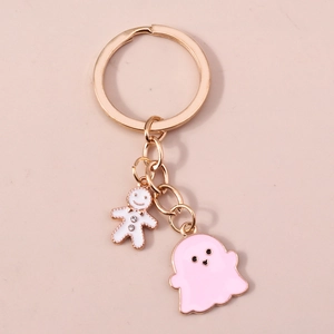 Détail d'un porte-clés doré avec charms de fantôme rose et bonhomme en pain d'épices