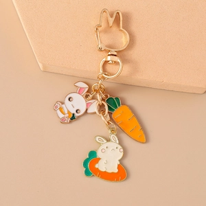 Détail de breloques carotte et lapin blanc sur un porte-clés en émail plaqué or