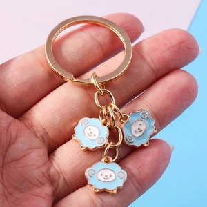 Cute cartoon sheep keychain with blue alpaca charms held in hand for backpack decor