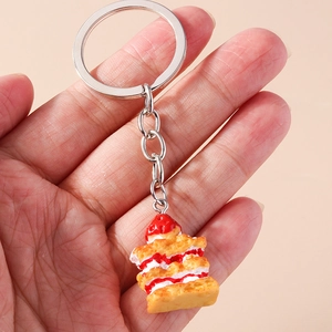 Realistic napoleon cake keychain with strawberry topping held in hand for bag decor