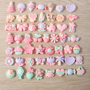 Makro-Detail von Pastell-Harz-Cabochons mit Tieren und Früchten für DIY-Schmuckherstellung