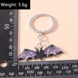 Detail shot of a 5.6g gothic cartoon bat keychain with purple wings on a pink background