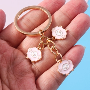 Cute cartoon pink sheep keychain with gold metal plating displayed on hand