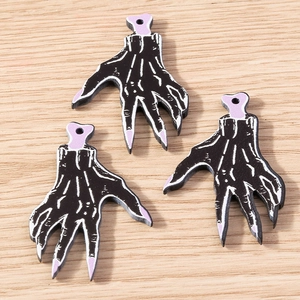 Detailed macro view of black skeleton hand charms with purple bone accents for DIY jewelry