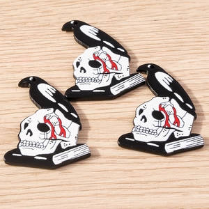 Gothic skull pendants with black raven on a wooden surface for DIY jewelry making