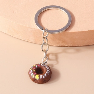 Macro detail of brown chocolate donut keychain with colorful sprinkles on a pink stand