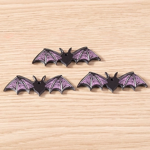 Close-up of black resin Halloween bat charms with purple wings for DIY jewelry crafting