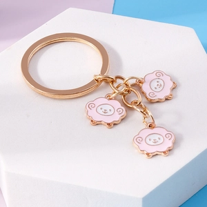 Close-up of golden metal keychain featuring three cute pink alpaca and sheep charms