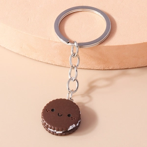 Detail of creative chocolate cookie keychain with white cream filling and a cute smiling face