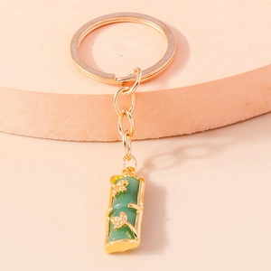 Macro view of gold bamboo charm keychain with green emerald faux jade and floral detail