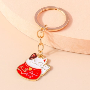 Close-up of golden lucky cat keychain with red and white enamel and lucky symbols