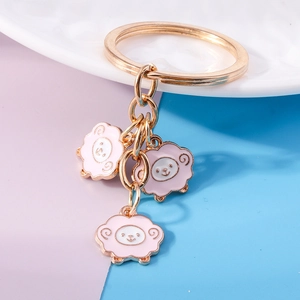 Close-up of pink sheep charms with golden key ring on a colorful background