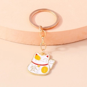 Detail of golden Maneki Neko keychain with white enamel cat and lucky charms