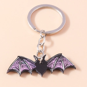 Detailed close-up of a cartoon bat keychain with purple wings on pink background