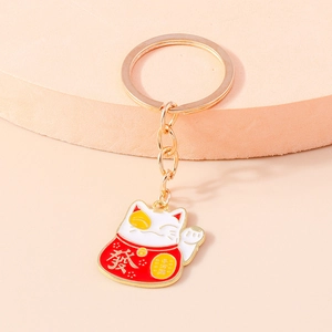Detail of red and gold Maneki Neko keychain with traditional Chinese lucky characters