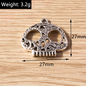 Detailed close-up of a silver-toned hollow skull pendant with intricate carved plant patterns