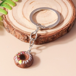 Detailed view of brown chocolate donut keychain with white lettering on wood