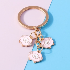 Detail of three cute pink enamel sheep charms hanging on a golden keychain ring