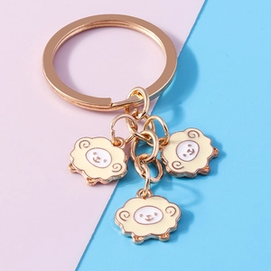 Detail of cute golden cartoon sheep keychain pendants with enamel finish on colorful background