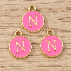 Detailed macro view of pink enamel letter N round pendants with golden metal frame