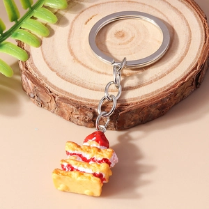Macro shot of realistic strawberry cake keychain on wooden slice with nature background