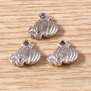 Three retro silver pumpkin charms for DIY jewelry making on a light wooden surface